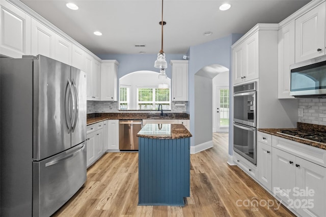 1009 Jerry Ln, Matthews, NC 28105 - kitchen featuring appliances with stainless steel finishes, arched walkways, a sink, a kitchen island, and white cabinets