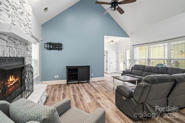 1009 Jerry Ln, Matthews, NC 28105 - living room featuring high vaulted ceiling, ceiling fan, light wood-style floors, baseboards, and a stone fireplace