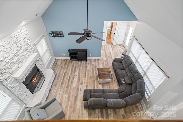1009 Jerry Ln, Matthews, NC 28105 - living room featuring high vaulted ceiling, a ceiling fan, a stone fireplace, wood finished floors, and healthy amount of natural light