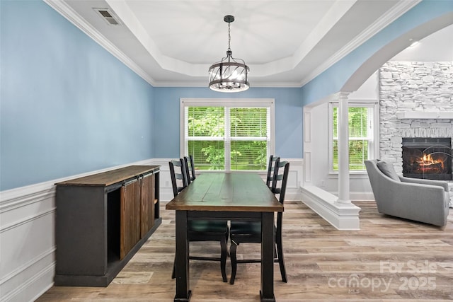 1009 Jerry Ln, Matthews, NC 28105 - dining area with a decorative wall, light wood-type flooring, a wainscoted wall, a stone fireplace, and arched walkways