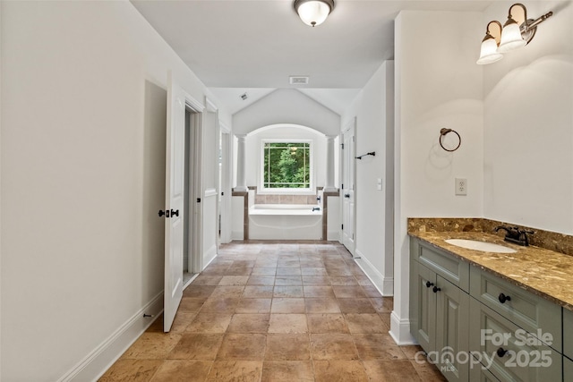 1009 Jerry Ln, Matthews, NC 28105 - full bath with baseboards, vanity, a bath, stone finish floors, and lofted ceiling