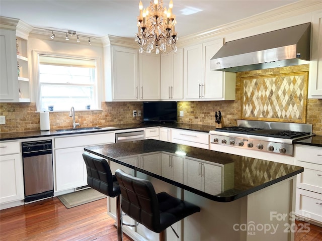 530 E Rutledge Ave, Gaffney, SC 29340 - kitchen with wall chimney exhaust hood, stainless steel appliances, a chandelier, tasteful backsplash, and a kitchen island