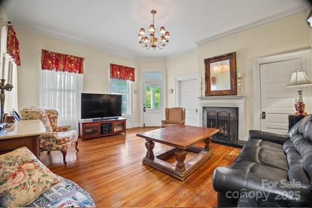 530 E Rutledge Ave, Gaffney, SC 29340 - living room with healthy amount of natural light, light wood finished floors, a chandelier, ornamental molding, and a fireplace with raised hearth