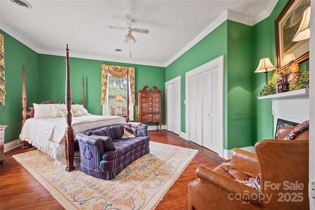 530 E Rutledge Ave, Gaffney, SC 29340 - bedroom featuring two closets, a glass covered fireplace, ornamental molding, wood finished floors, and ceiling fan
