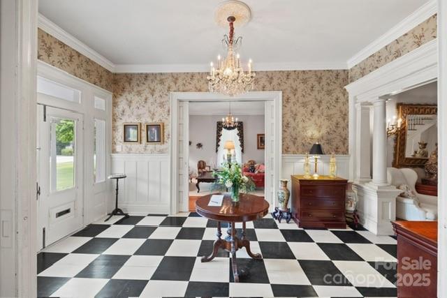 530 E Rutledge Ave, Gaffney, SC 29340 - entryway with a chandelier, a wainscoted wall, decorative columns, dark flooring, and a decorative wall