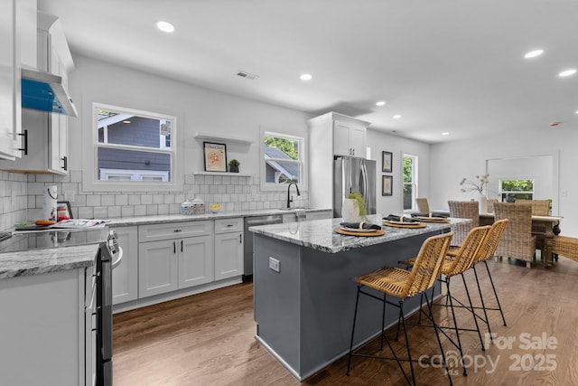 1922 Thomas Ave, Charlotte, NC 28205 - kitchen featuring appliances with stainless steel finishes, recessed lighting, a kitchen bar, dark wood-style flooring, and white cabinets