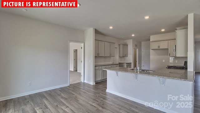 8036 Kennesaw Dr, Gastonia, NC 28056 - kitchen featuring a sink, a peninsula, a kitchen bar, gray cabinetry, and decorative backsplash