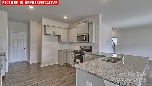 8036 Kennesaw Dr, Gastonia, NC 28056 - kitchen with appliances with stainless steel finishes, a sink, a peninsula, light stone countertops, and dark wood-type flooring