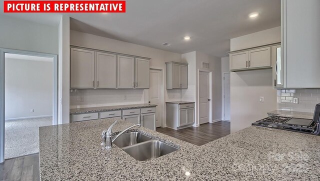 8036 Kennesaw Dr, Gastonia, NC 28056 - kitchen with gray cabinets, a sink, tasteful backsplash, light stone counters, and baseboards