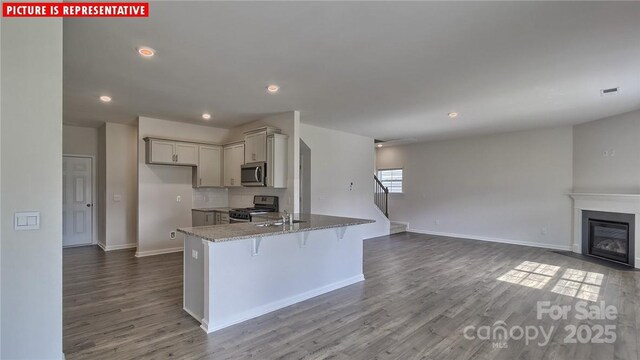 8036 Kennesaw Dr, Gastonia, NC 28056 - kitchen with stainless steel appliances, dark wood-type flooring, a kitchen breakfast bar, light stone counters, and open floor plan