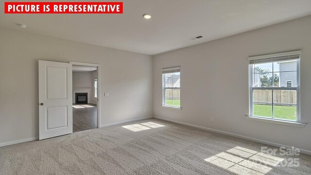 8036 Kennesaw Dr, Gastonia, NC 28056 - carpeted empty room featuring baseboards, plenty of natural light, a glass covered fireplace, a smoke detector, and recessed lighting