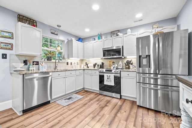 4236 Carrington Ct SW, Concord, NC 28027 - kitchen with stainless steel appliances, white cabinets, tasteful backsplash, light wood finished floors, and recessed lighting