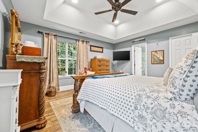 4236 Carrington Ct SW, Concord, NC 28027 - bedroom featuring wood-type flooring, a tray ceiling, a ceiling fan, and baseboards