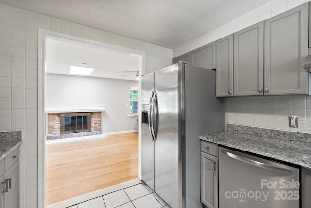 1810 13th Ave NE, Hickory, NC 28601 - kitchen with appliances with stainless steel finishes, gray cabinets, tile walls, light tile patterned floors, and a glass covered fireplace