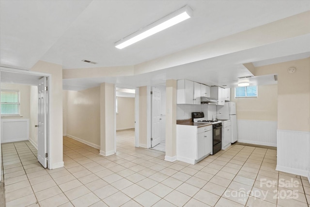 1810 13th Ave NE, Hickory, NC 28601 - kitchen with range with gas cooktop, under cabinet range hood, white cabinets, light tile patterned floors, and wainscoting