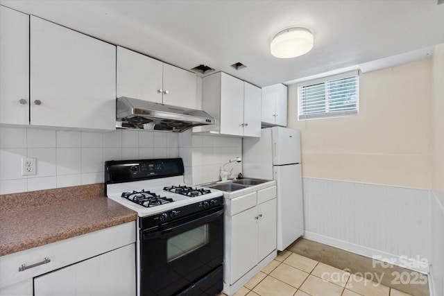 1810 13th Ave NE, Hickory, NC 28601 - kitchen with gas stove, under cabinet range hood, freestanding refrigerator, white cabinets, and a wainscoted wall