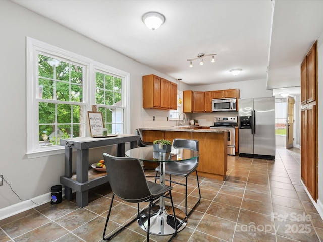 7317 Red Branch Ln, Charlotte, NC 28226 - kitchen with stainless steel appliances, brown cabinetry, a peninsula, a sink, and tile patterned floors