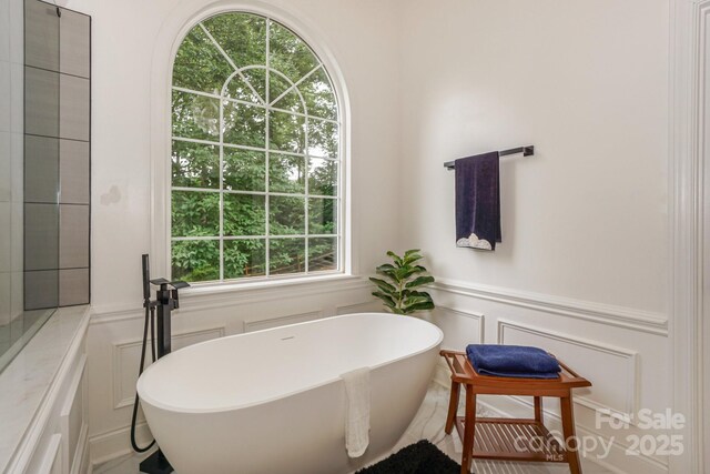 14831 Charterhouse Ln, Huntersville, NC 28078 - bathroom with a decorative wall, a soaking tub, and a wainscoted wall