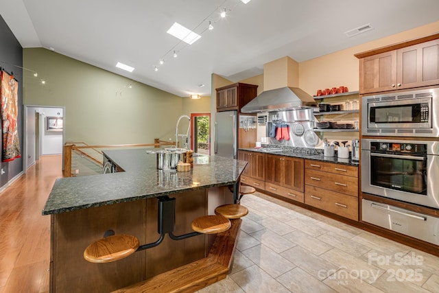 1760 Winding Creek Dr, Waynesville, NC 28786 - kitchen featuring stainless steel appliances, a warming drawer, vaulted ceiling, open shelves, and a kitchen island with sink