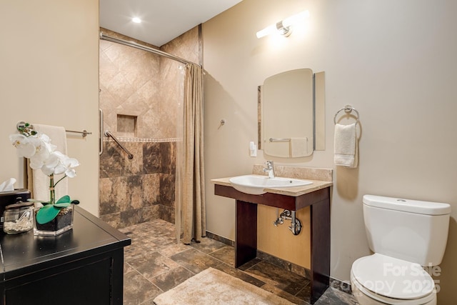 1760 Winding Creek Dr, Waynesville, NC 28786 - bathroom featuring a tile shower, toilet, baseboards, stone finish floors, and a sink