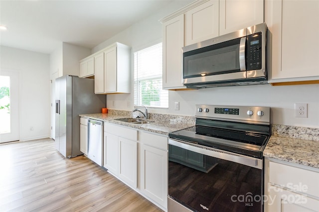 3073 Langhorne Ave SW, Concord, NC 28027 - kitchen featuring stainless steel appliances, a sink, light wood-type flooring, white cabinetry, and light stone countertops