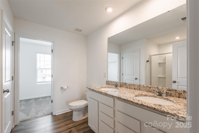 3073 Langhorne Ave SW, Concord, NC 28027 - bathroom featuring wood finished floors, double vanity, toilet, a shower, and baseboards