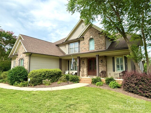 141 Weathers Creek Rd, Troutman, NC 28166 - traditional home with brick siding, a porch, a front lawn, and roof with shingles