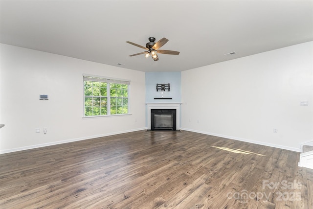 347 Carolina Hemlock Dr, Locust, NC 28097 - unfurnished living room with wood finished floors, a ceiling fan, a glass covered fireplace, and baseboards