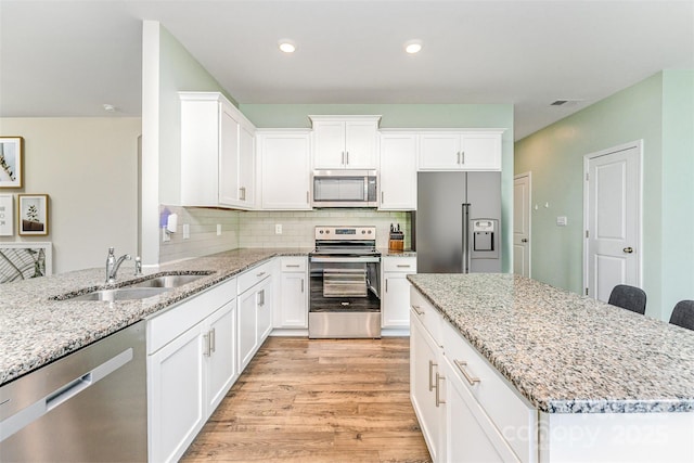 347 Carolina Hemlock Dr, Locust, NC 28097 - kitchen featuring stainless steel appliances, a sink, light wood-style floors, light stone countertops, and recessed lighting
