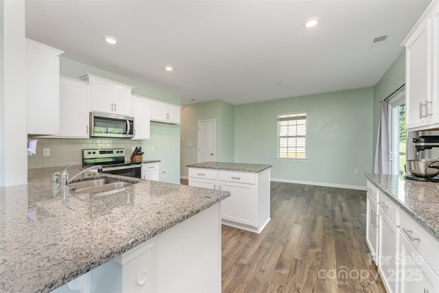 347 Carolina Hemlock Dr, Locust, NC 28097 - kitchen featuring appliances with stainless steel finishes, a sink, tasteful backsplash, dark wood-style flooring, and white cabinetry