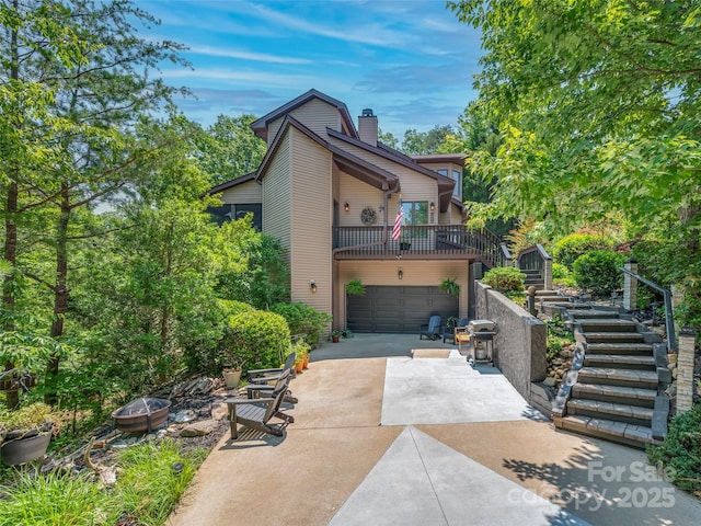 117 Eagles Crest Way, Lake Lure, NC 28746 - view of front of home featuring an outdoor fire pit, concrete driveway, an attached garage, stairway, and a chimney