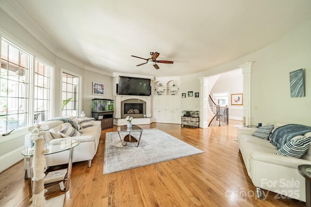 1032 Seminole Dr, Waxhaw, NC 28173 - living room featuring a ceiling fan, a fireplace with raised hearth, wood finished floors, stairway, and ornate columns