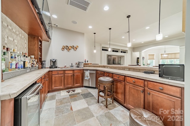 1032 Seminole Dr, Waxhaw, NC 28173 - kitchen with a peninsula, brown cabinetry, arched walkways, hanging light fixtures, and recessed lighting