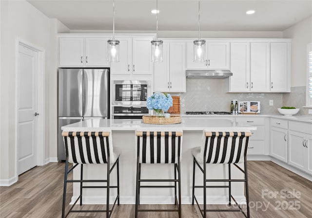 5481 Comiskey Aly, Kannapolis, NC 28081 - kitchen featuring appliances with stainless steel finishes, under cabinet range hood, a kitchen island, white cabinetry, and recessed lighting