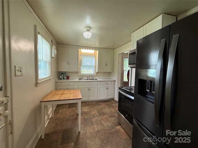 317 Heilig Ave, Salisbury, NC 28144 - kitchen with stainless steel appliances, white cabinets, a sink, baseboards, and stone finish floors