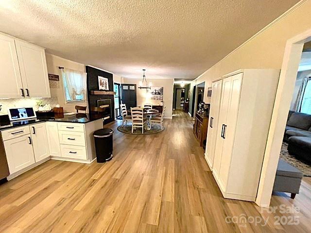 135 Michelle Dr, Ellenboro, NC 28040 - kitchen featuring light wood-style floors, a textured ceiling, white cabinets, a chandelier, and dark countertops