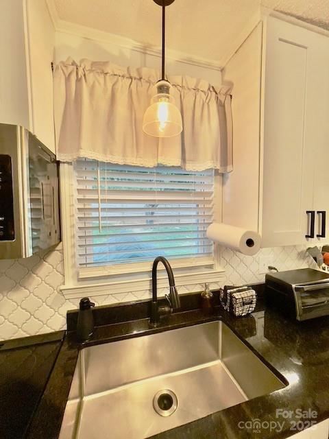135 Michelle Dr, Ellenboro, NC 28040 - detailed view of white cabinetry, decorative backsplash, a sink, ornamental molding, and hanging light fixtures