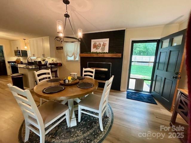 135 Michelle Dr, Ellenboro, NC 28040 - dining area with crown molding, light wood-type flooring, and a fireplace
