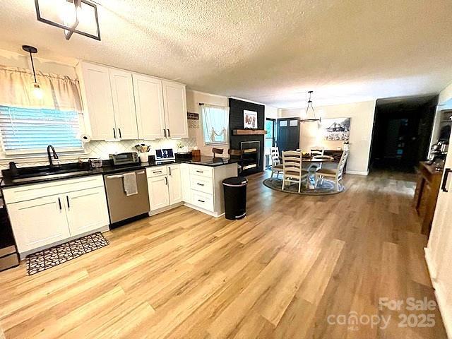 135 Michelle Dr, Ellenboro, NC 28040 - kitchen featuring stainless steel dishwasher, a textured ceiling, light wood-style floors, a sink, and white cabinetry