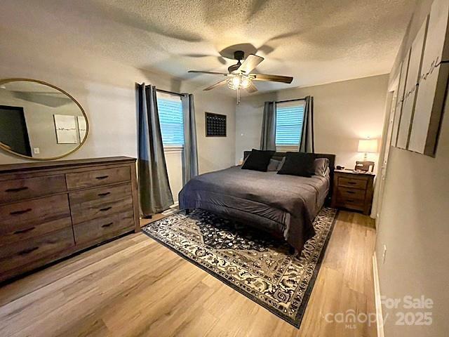 135 Michelle Dr, Ellenboro, NC 28040 - bedroom featuring light wood finished floors, a textured ceiling, multiple windows, and a ceiling fan