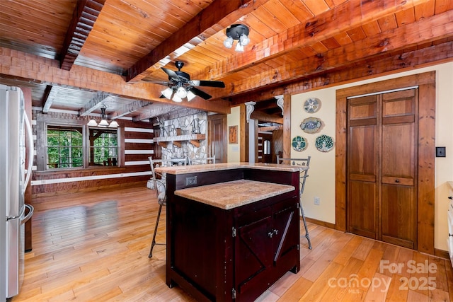2709 Blythe Rd, Waxhaw, NC 28173 - kitchen with freestanding refrigerator, wooden ceiling with exposed beams, light wood-style floors, a kitchen bar, and ceiling fan