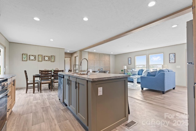 977 Myers Mill Rd, Olin, NC 28660 - kitchen featuring light wood-style floors, gray cabinetry, an island with sink, stainless steel dishwasher, and a textured ceiling