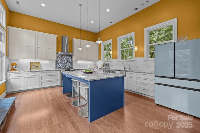 2009 Waterbury Ln, Waxhaw, NC 28173 - kitchen featuring wall chimney exhaust hood, freestanding refrigerator, white cabinets, tasteful backsplash, and light wood finished floors