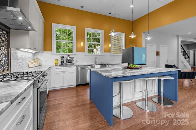 2009 Waterbury Ln, Waxhaw, NC 28173 - kitchen with appliances with stainless steel finishes, wall chimney range hood, dark wood finished floors, a kitchen bar, and recessed lighting