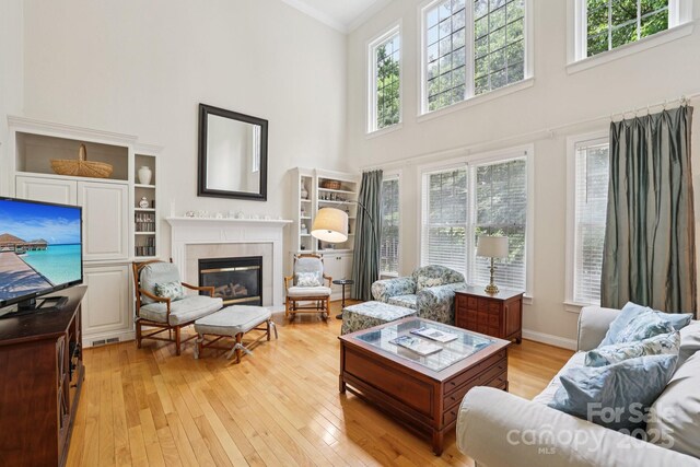 11103 Fountaingrove Dr, Charlotte, NC 28262 - living room featuring a high ceiling, healthy amount of natural light, light wood-style flooring, crown molding, and a tile fireplace