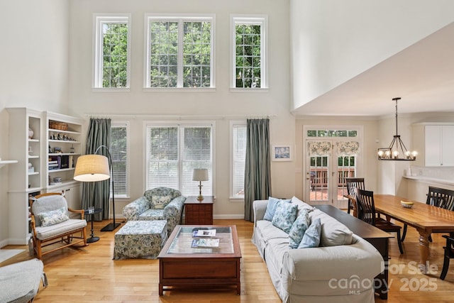 11103 Fountaingrove Dr, Charlotte, NC 28262 - living room featuring a towering ceiling, a chandelier, plenty of natural light, and light wood-type flooring