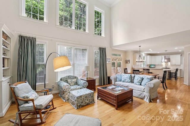 11103 Fountaingrove Dr, Charlotte, NC 28262 - living room featuring light wood-type flooring, a towering ceiling, healthy amount of natural light, and crown molding