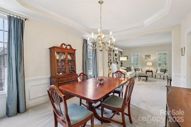 11103 Fountaingrove Dr, Charlotte, NC 28262 - dining area featuring a chandelier, a tray ceiling, light colored carpet, crown molding, and wainscoting