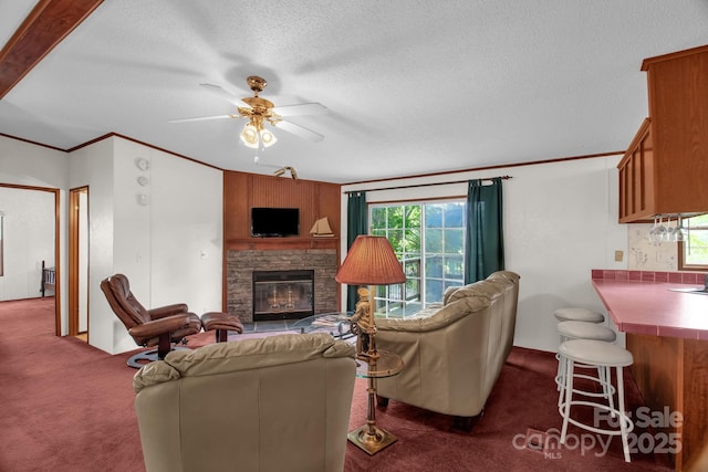 7232 Executive Cir, Denver, NC 28037 - living room with dark carpet, a stone fireplace, a textured ceiling, a ceiling fan, and crown molding