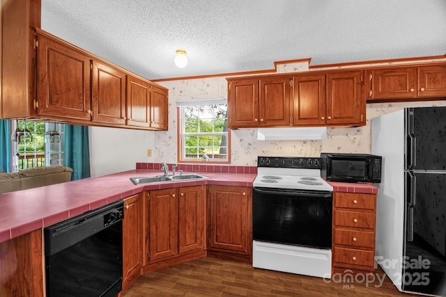 7232 Executive Cir, Denver, NC 28037 - kitchen with black appliances, a sink, tile counters, under cabinet range hood, and wallpapered walls
